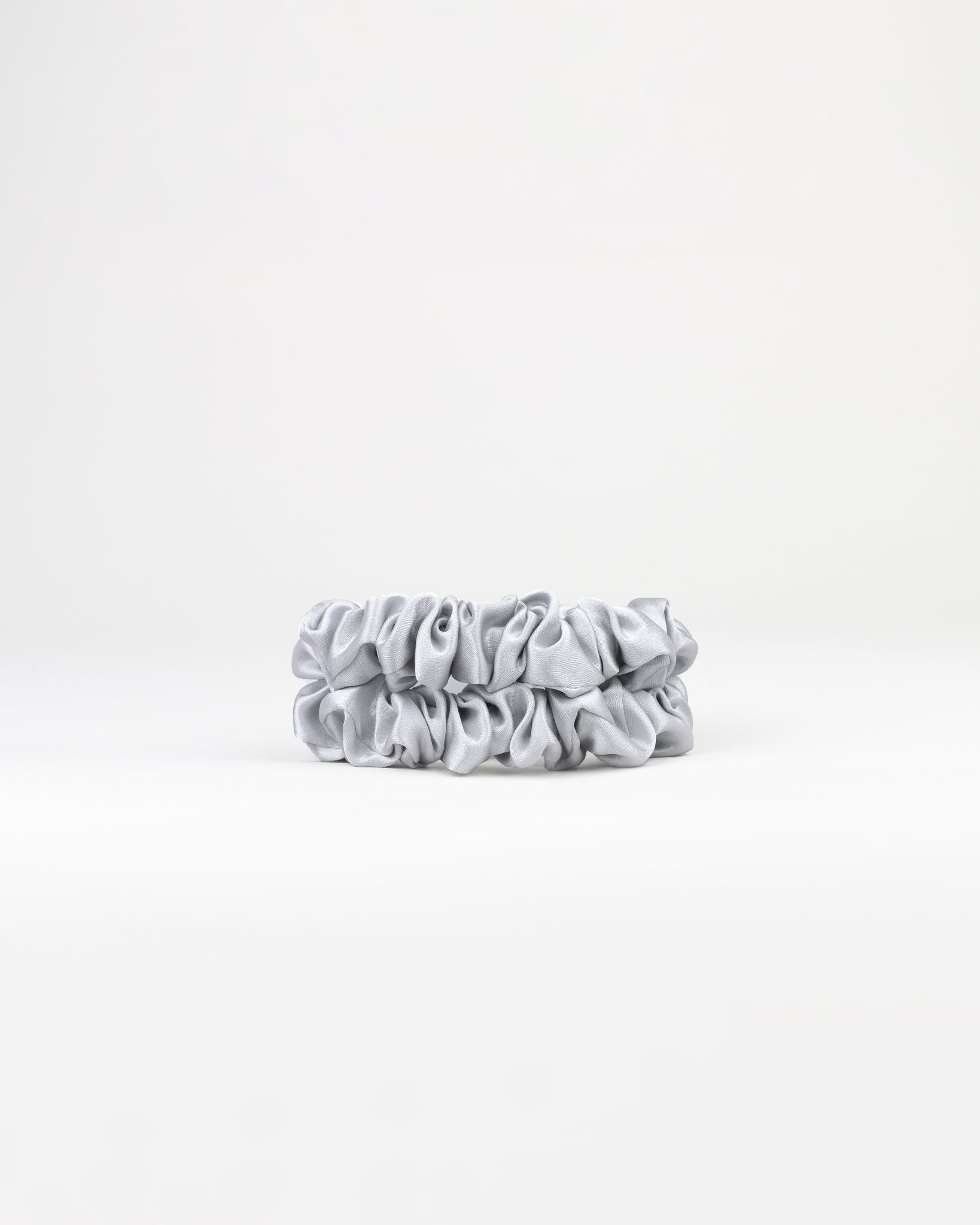 Two grey scrunchies on a white background