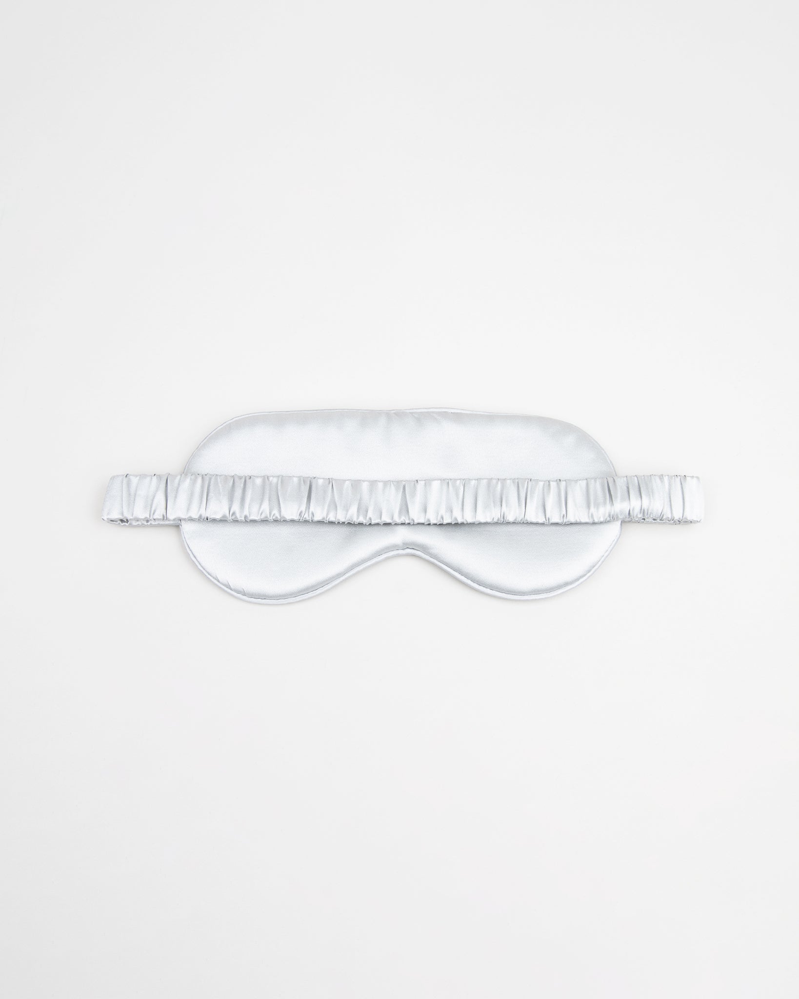Light grey silk sleep mask with white strap on a light gray background