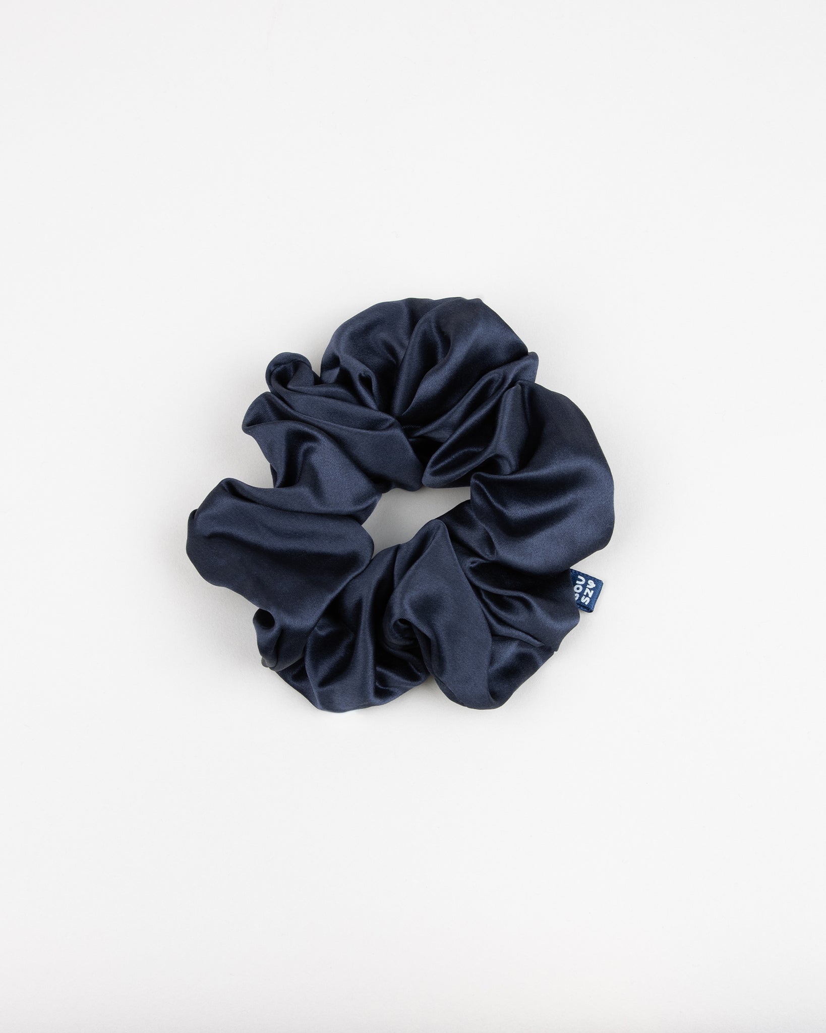 Large navy blue silk scrunchie with a souszy brand label on a white background